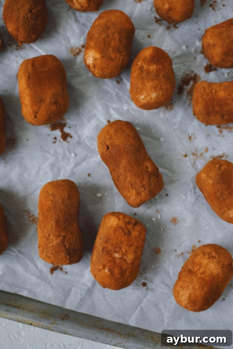 Looking down at Irish Potato Candy on a sheet pan ready to rest in the fridge and set up.