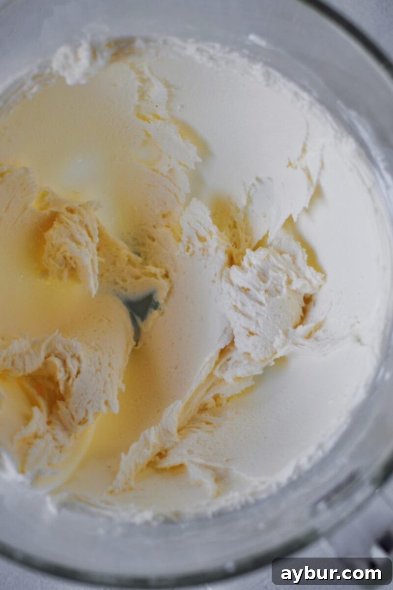 Blending the powdered sugar, butter, and cream cheese together to form the base of the candy.