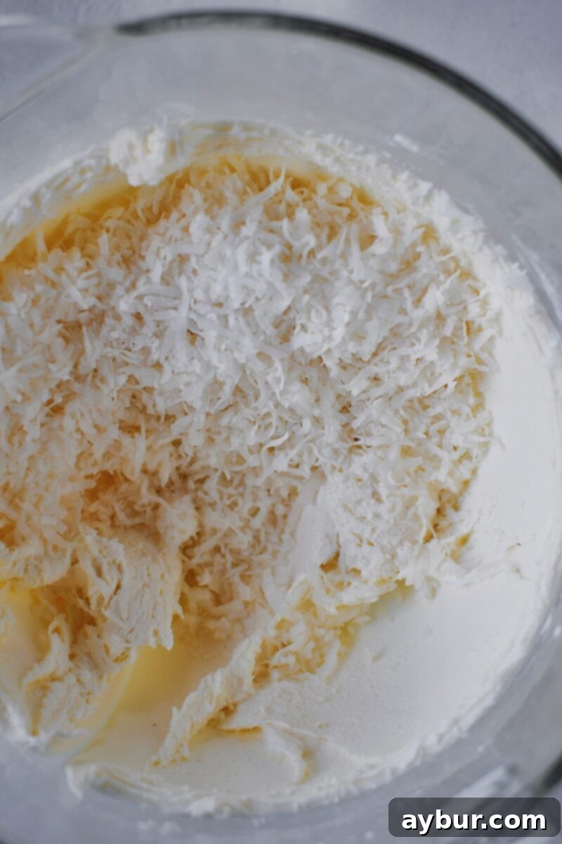 Stirring in the coconut into the butter and cream cheese mixture.