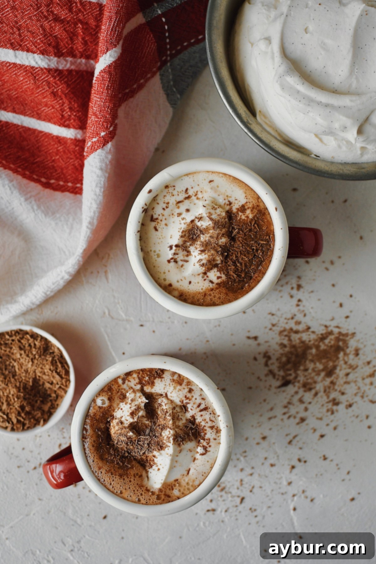 Simple 3-Ingredient Nutella Hot Chocolate 4 Close-up overhead view of two mugs of Nutella Hot Chocolate, beautifully adorned with fresh whipped cream and delicate chocolate shavings.