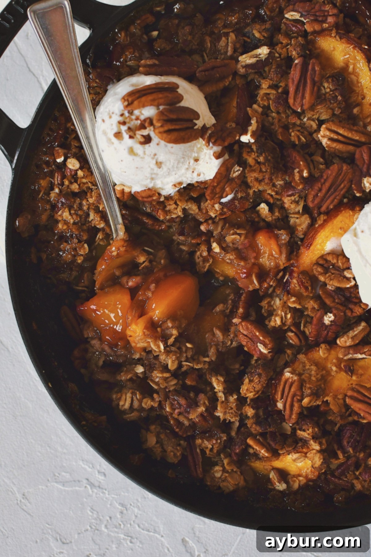 A generous serving of warm Peach Pecan Crisp being dished out, ready to be enjoyed.
