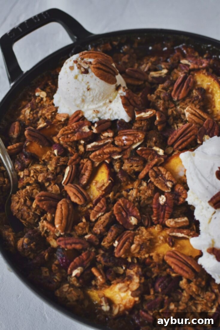 Peach Pecan Crisp just after baking, topped with extra toasted pecans and vanilla ice cream.