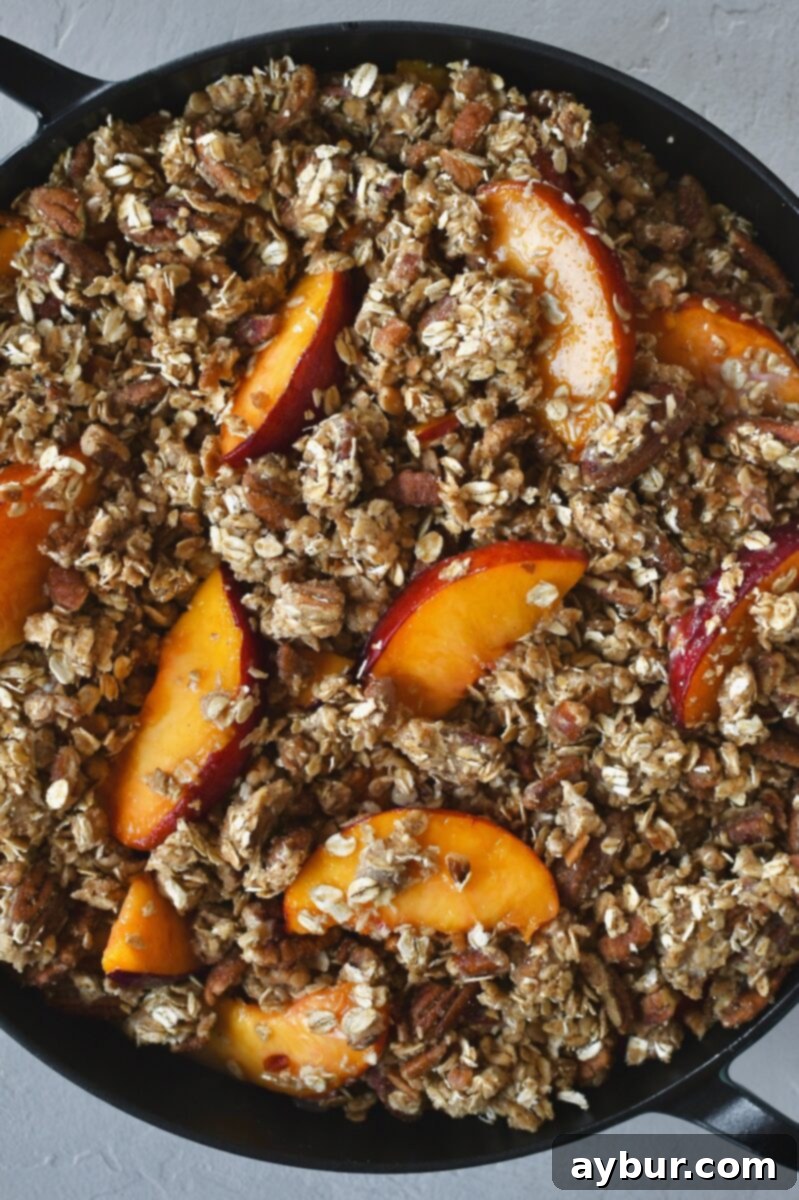 The oat crisp mixture spread over the peaches, with a light toss revealing some peach slices on top.