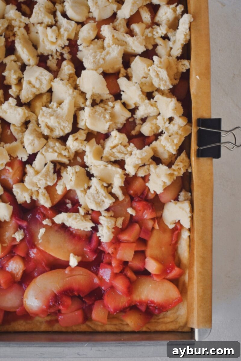 Hand crumbling reserved shortbread dough over the peach filling before the final bake.