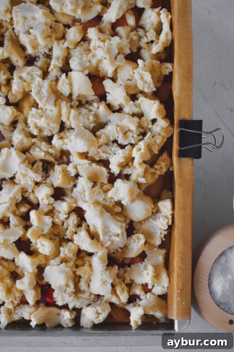 Evenly crumbled reserved shortbread dough topping over the peach layer.