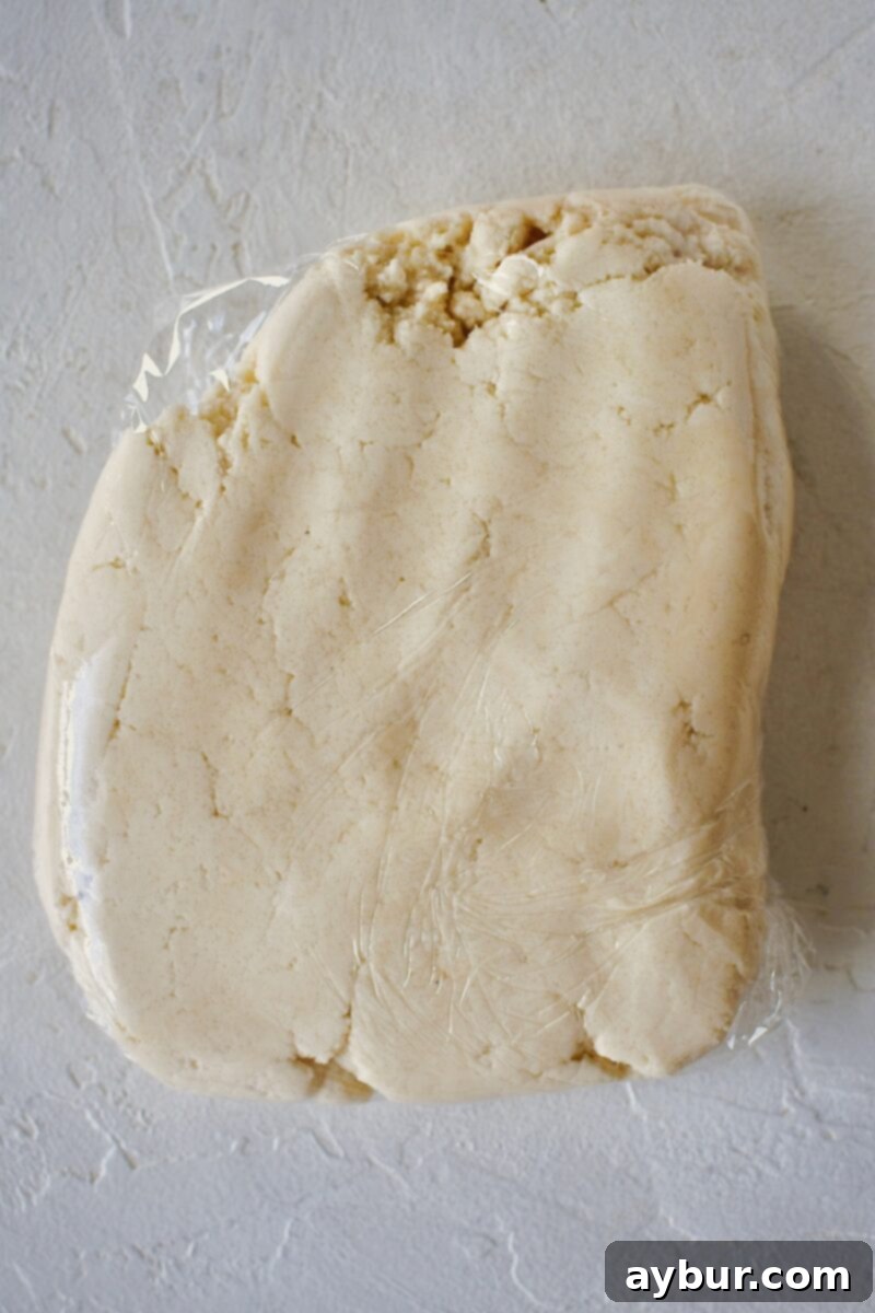 A portion of shortbread dough wrapped in plastic wrap, set aside for the topping.