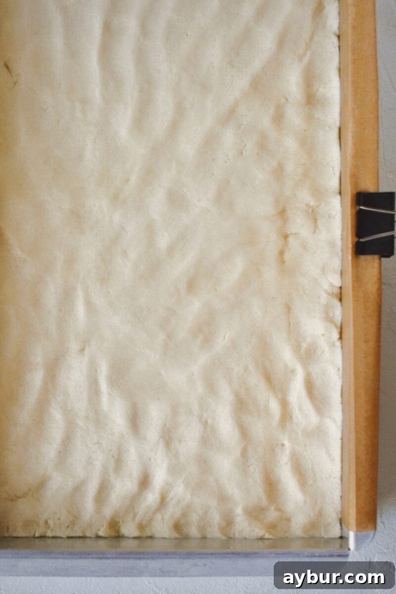 Shortbread dough pressed evenly into the bottom of a 9x13 inch pan, forming the crust.