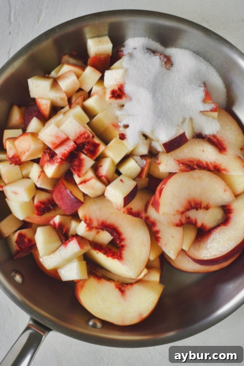 Fresh white peaches, sugar, and lemon juice in a skillet before cooking.