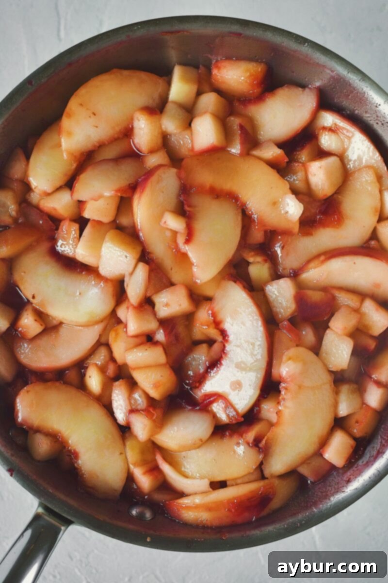 Cooked peaches with sugar and lemon juice, thickened and syrupy, in a skillet.