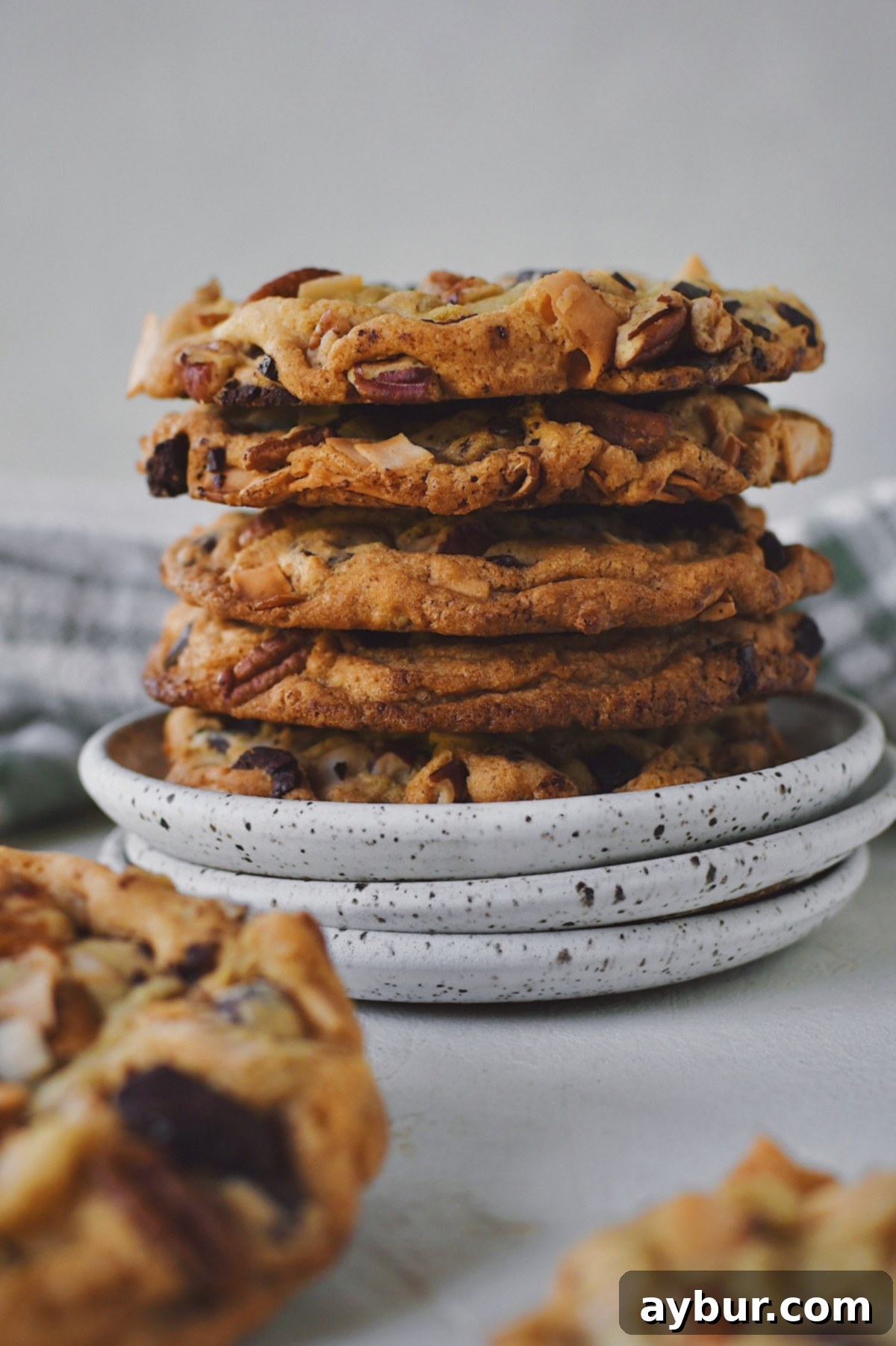 Freshly baked Coconut Pecan Chocolate Chip Cookies, generously topped and perfectly golden, stacked high on a ceramic plate ready to be enjoyed.