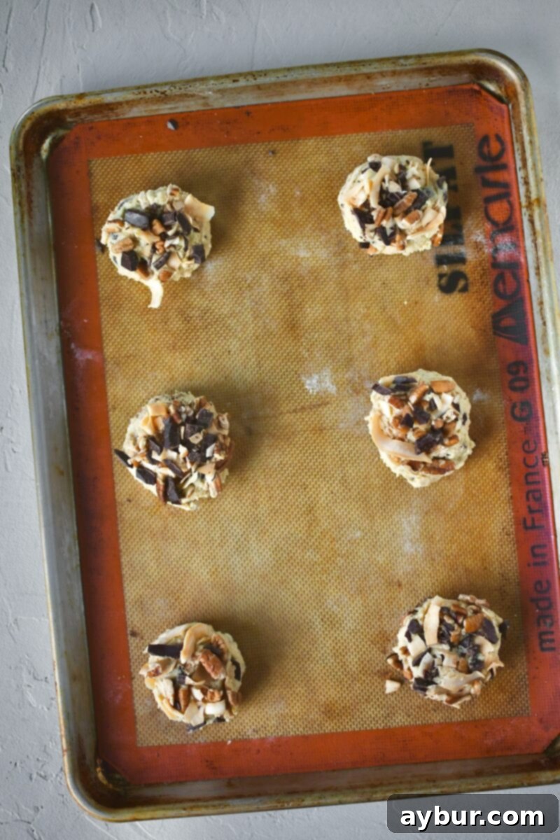 Rows of perfectly topped cookie dough balls, neatly spaced on a baking sheet lined with parchment paper, awaiting their transformation in the preheated oven.