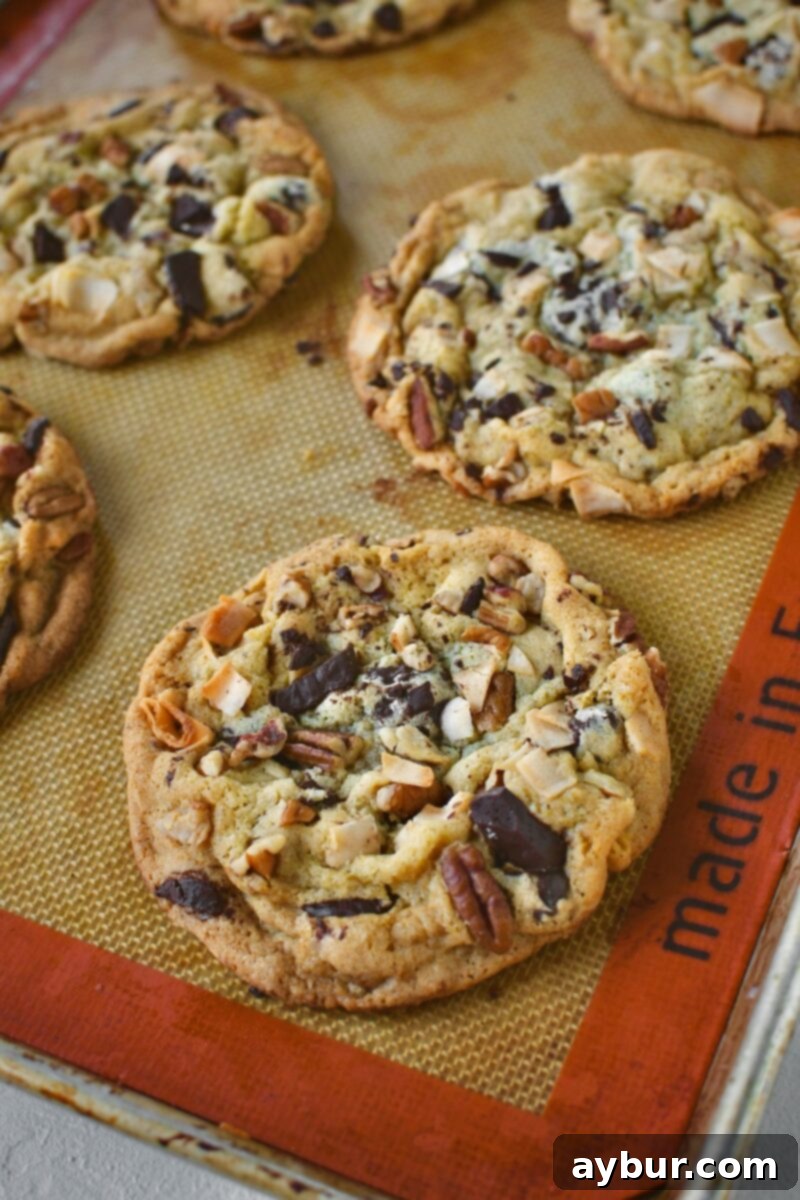 A tempting tray of freshly baked Coconut Pecan Chocolate Chip Cookies, cooling on their baking sheet, filling the kitchen with their sweet aroma.