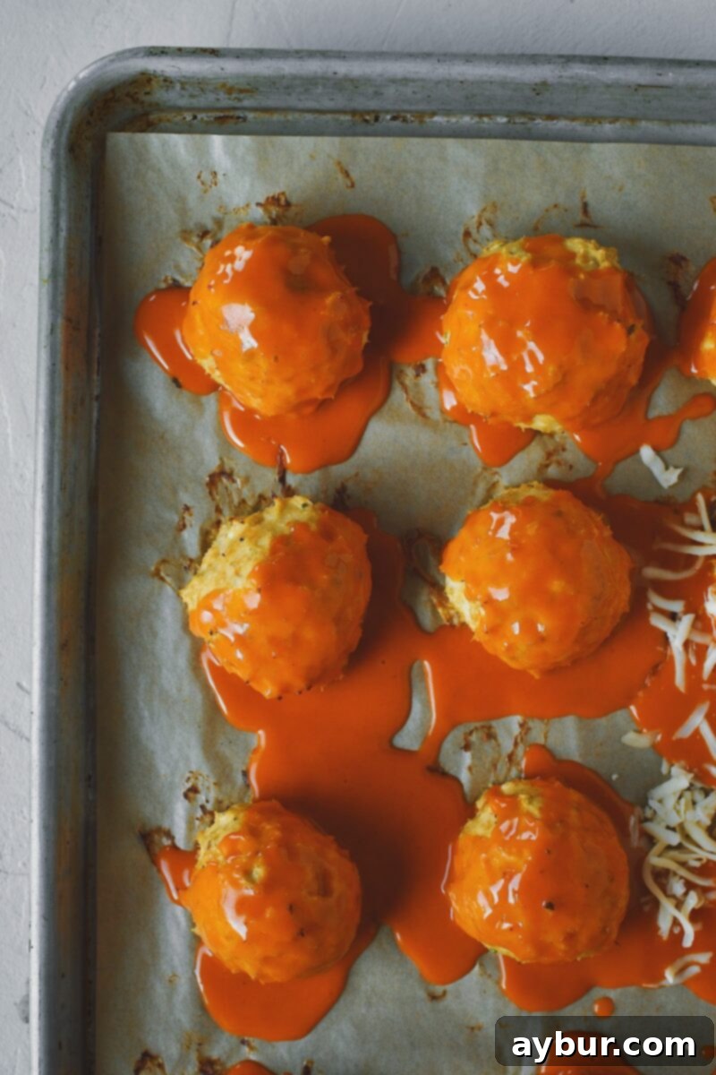 Topping meatballs with buffalo sauce.