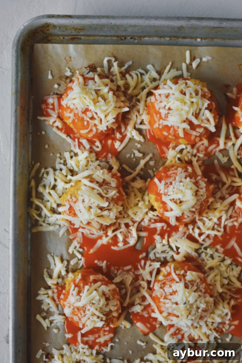 Topping meatballs with white cheddar cheese.