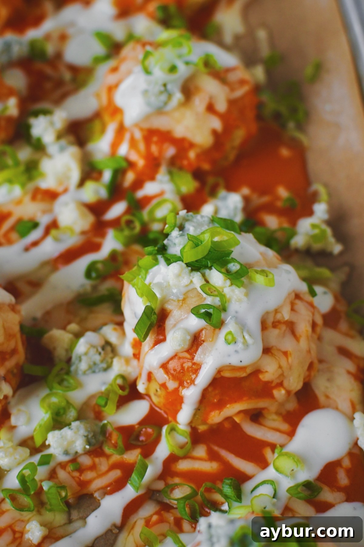 After melting the cheese, Buffalo Chicken Meatballs just out of the oven and topped with chopped green onions and ranch dressing.