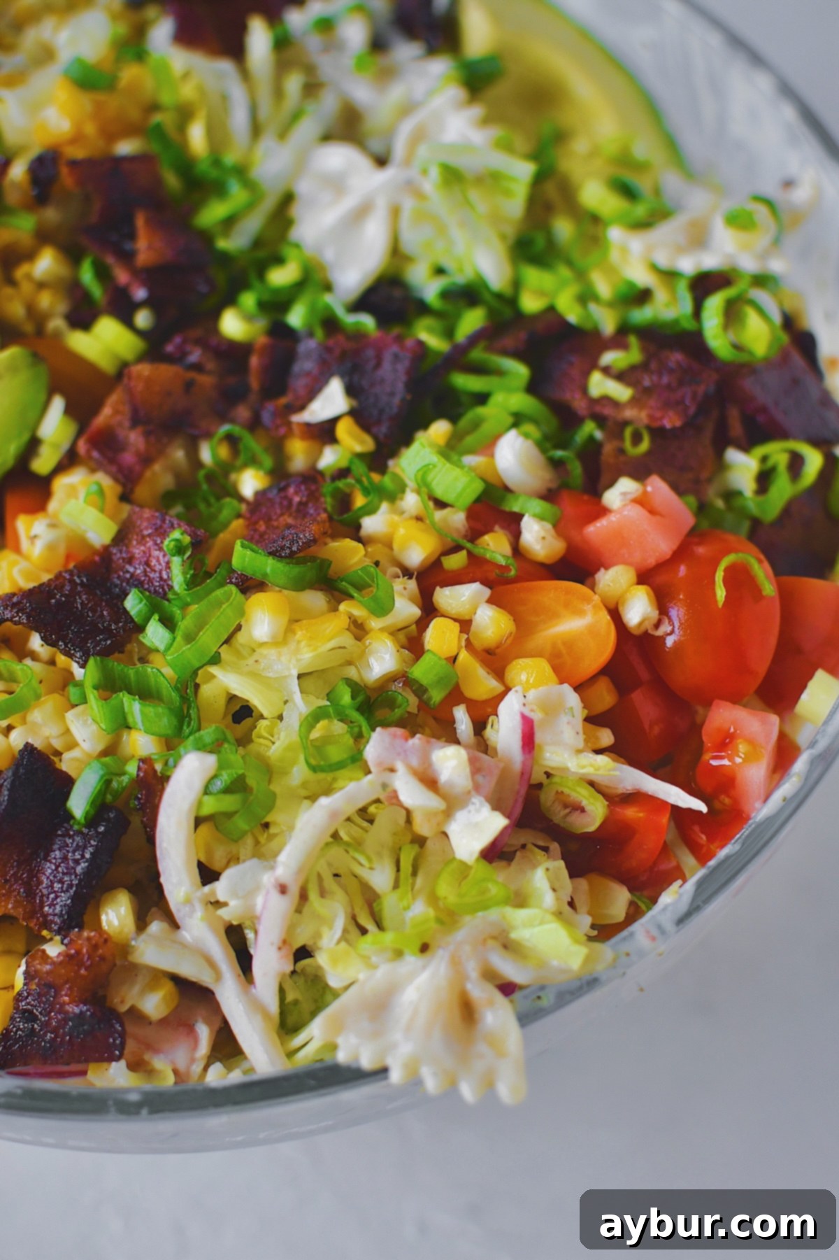 Looking into a large, appealing bowl of BLT Pasta Salad, richly topped with its signature ingredients and perfectly dressed, ready for enjoyment.