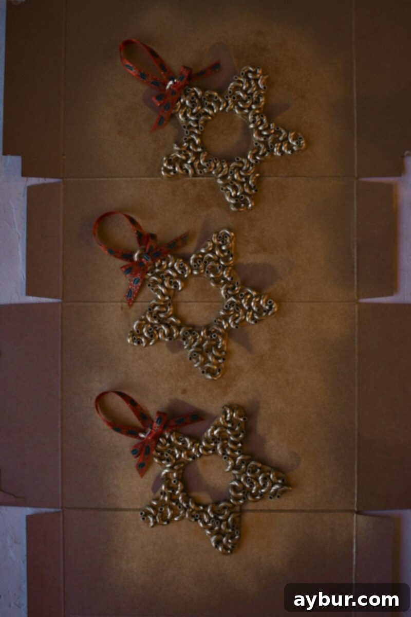 Macaroni pasta has all been glued on, after spray painting gold and adding a ribbon for hanging and a bow.