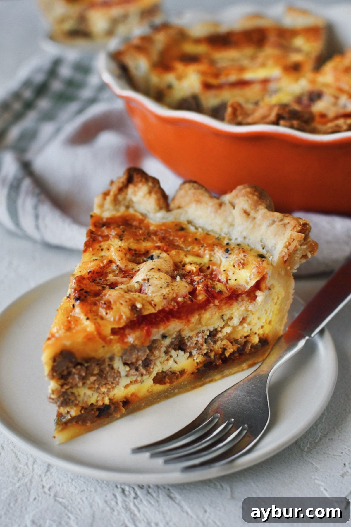 Loaded Cheeseburger Pie 2 View of all the layers of the cheeseburger pie, a slice on a small plate with a fork ready to eat.