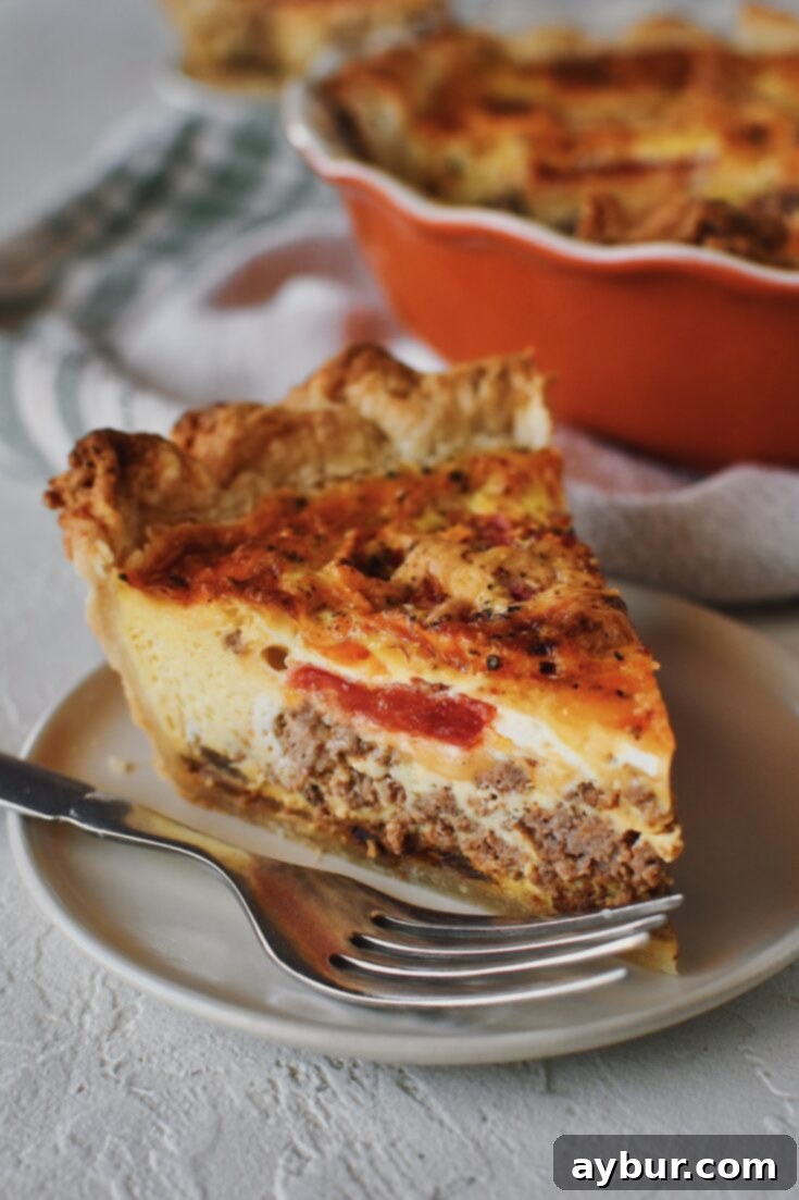 Loaded Cheeseburger Pie 4 Side profile of a slice of cheeseburger pie, on a plate with a fork next to it.