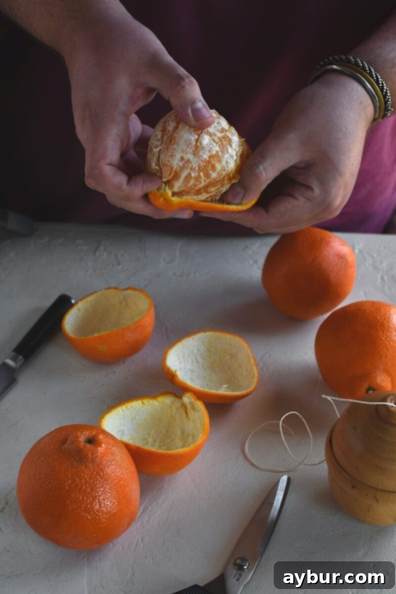 Fragrant Orange Star Garland 6 Detailed shot of a hand carefully detaching the peel from an orange, striving to keep the peel in one continuous, large piece.