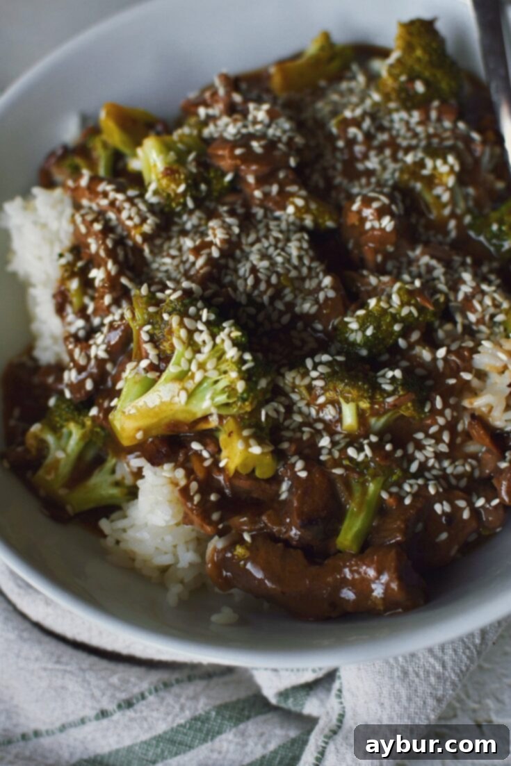 Looking into a bowl of Slow Cooker Beef and Broccoli topped with sesame seeds.