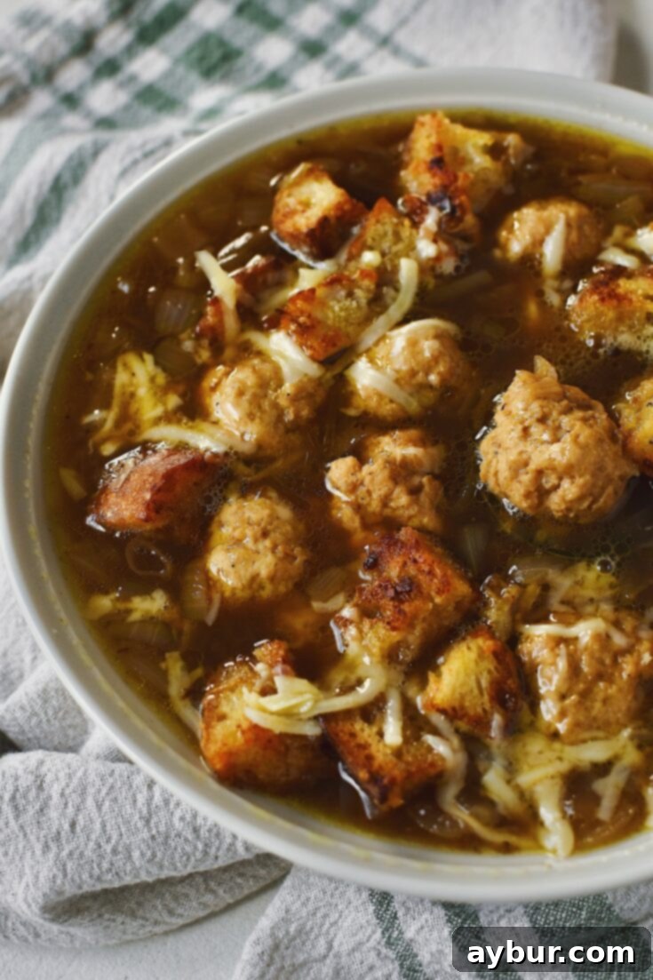 A top-down view of Cheesy French Onion Soup with mini chicken meatballs and Gruyere croutons, ready to be pinned.