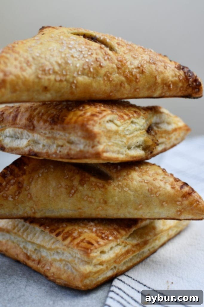 Close-up shot of a baked caramel apple turnover, showing the golden crust and caramelized apple filling