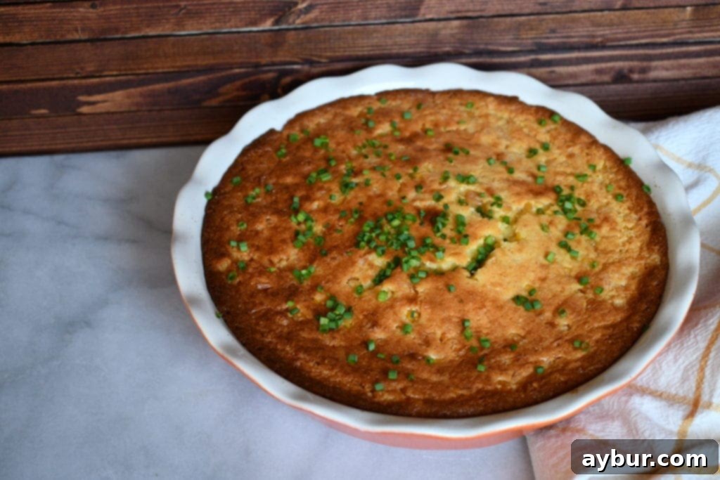 A close-up shot of the spoonbread in a serving dish, with a spoon having just scooped a portion, emphasizing its creamy texture.