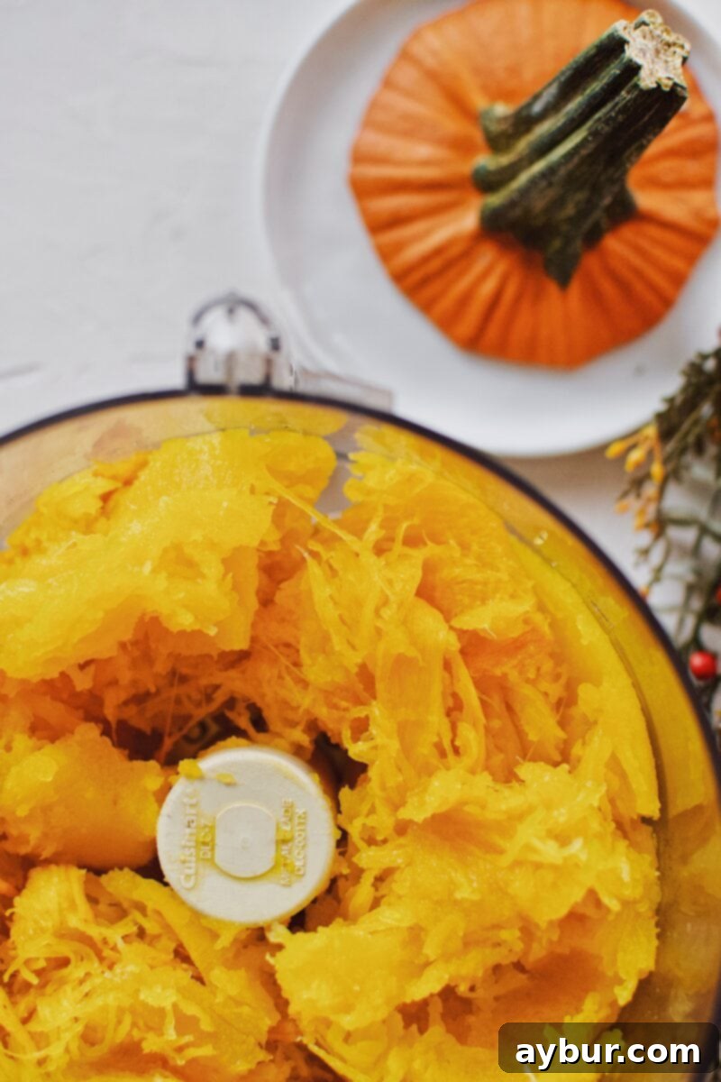 Golden Homemade Pumpkin Puree 9 Roasted pumpkin flesh, vibrant orange, placed in the bowl of a food processor, ready to be blended into a smooth puree.