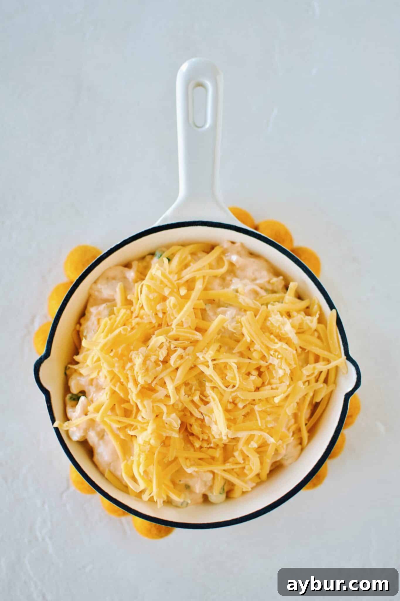 Buffalo Chicken Cheese Dip topped with cheddar cheese, ready for the oven to bake to a golden perfection.