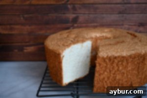 A freshly baked, perfectly golden Angel Food Cake cooling upside down, showcasing its impressive height and airy structure. This image represents the delicate texture achieved with Joanna Gaines' recipe.