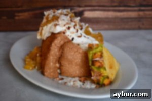 A close-up of a serving of Angel Food Cake, beautifully presented with a generous scoop of homemade pineapple brown sugar compote, garnished with a sprig of fresh mint, highlighting its vibrant flavors.