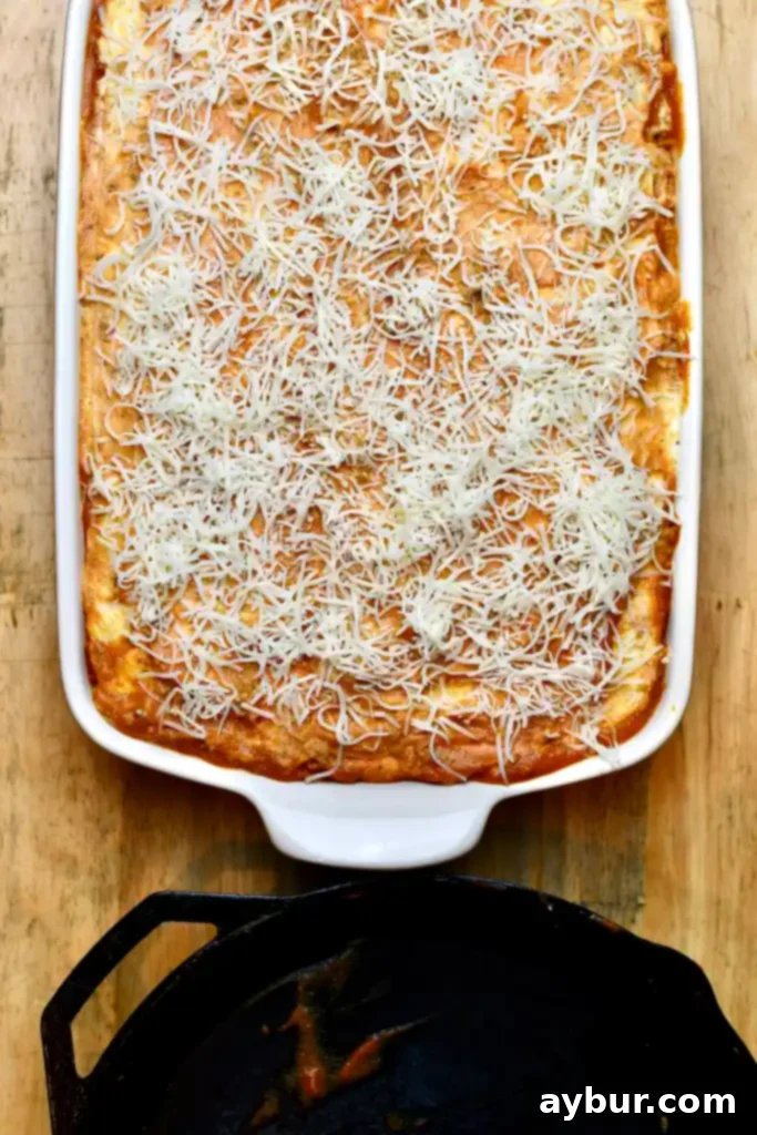 Lasagna in a baking dish, topped with cheese and covered with foil, ready to go into the oven