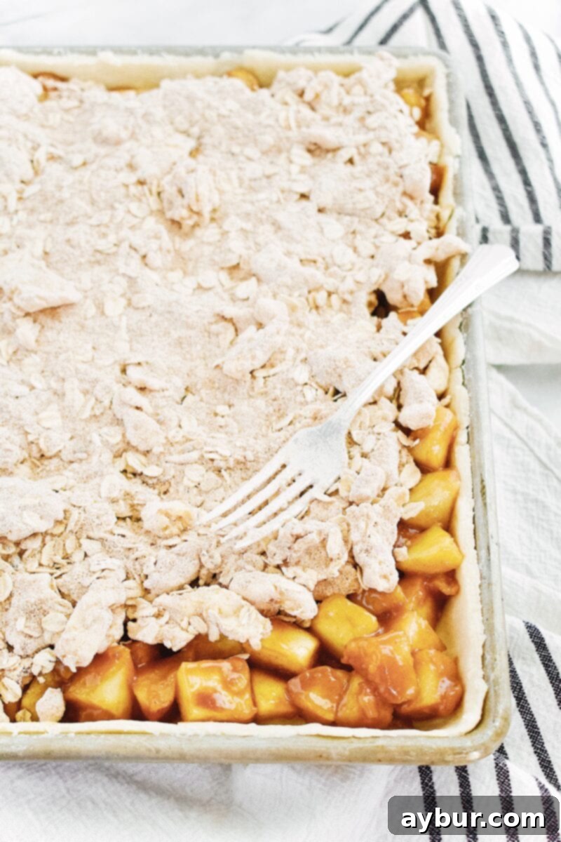 Pie dough being gently pressed into a rectangular sheet pan, forming the base for the slab pie.