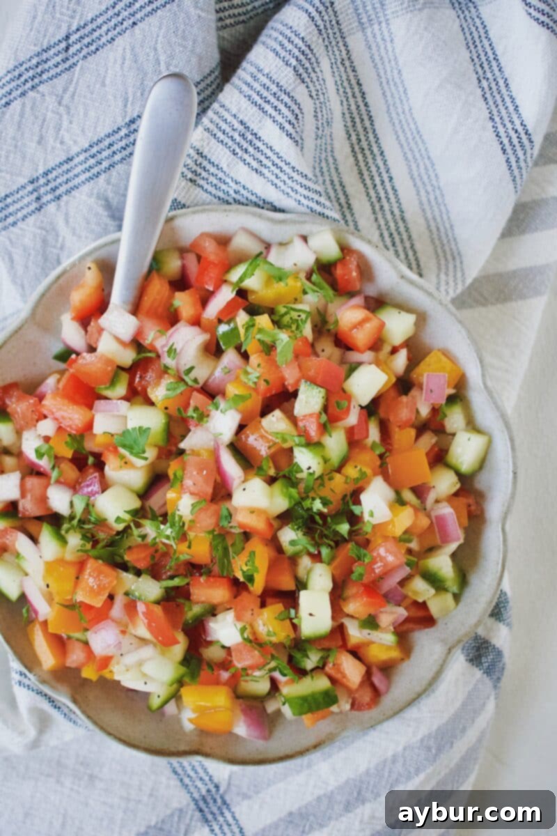 Greek Salsa Fresca 6 A bowl of vibrant Greek Pico de Gallo, freshly made and ready to be enjoyed, with a spoon for serving.