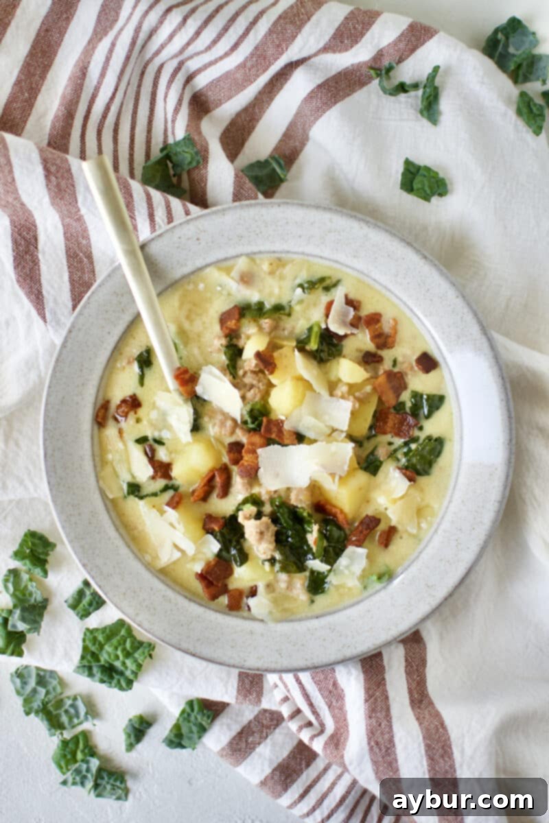 Chef's Signature Zuppa Toscana 12 A close-up shot of a spoon scooping into a creamy Zuppa Toscana soup, showing the texture of potatoes and sausage.