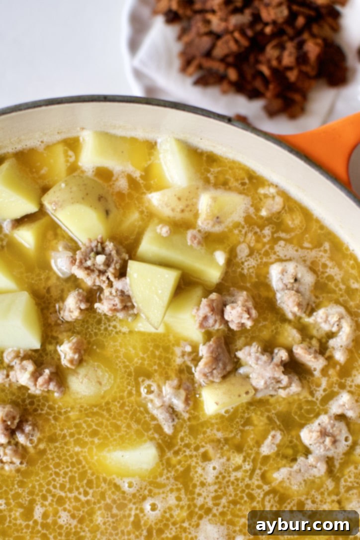 Chef's Signature Zuppa Toscana 6 Browned Italian sausage, chicken stock, and diced Yukon Gold potatoes cooking together in a large soup pot.