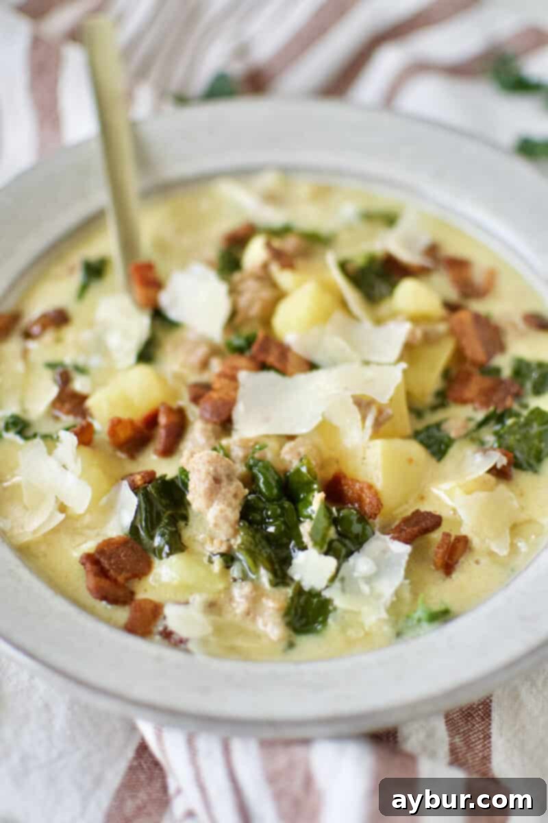 Chef's Signature Zuppa Toscana 9 A close-up of a rustic wooden table with two bowls of steaming Zuppa Toscana soup, garnished with parmesan and bacon, ready to be enjoyed with a spoon.